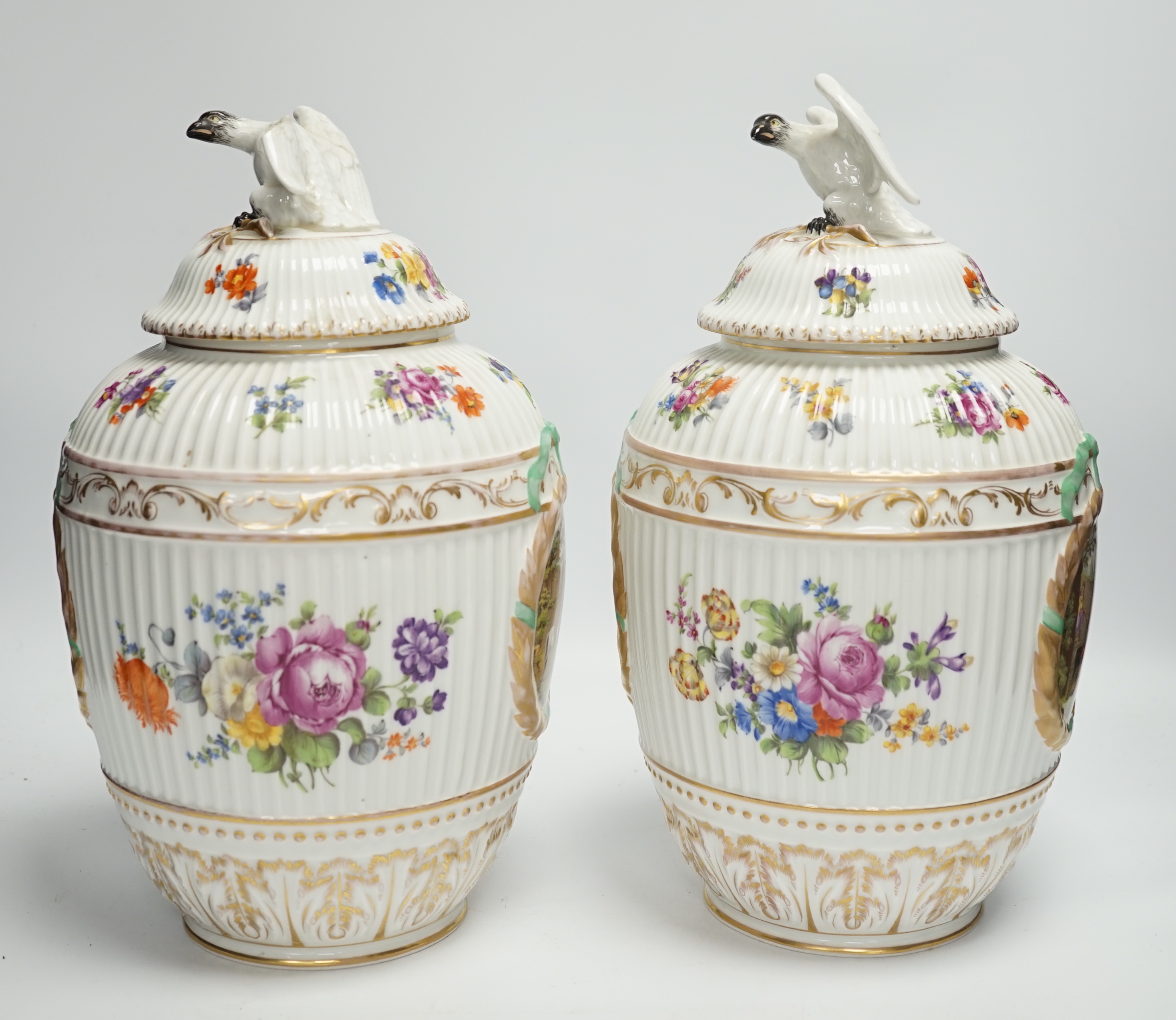 A pair of Continental floral decorated ribbed jars and covers with figural cartouches, 32cm high